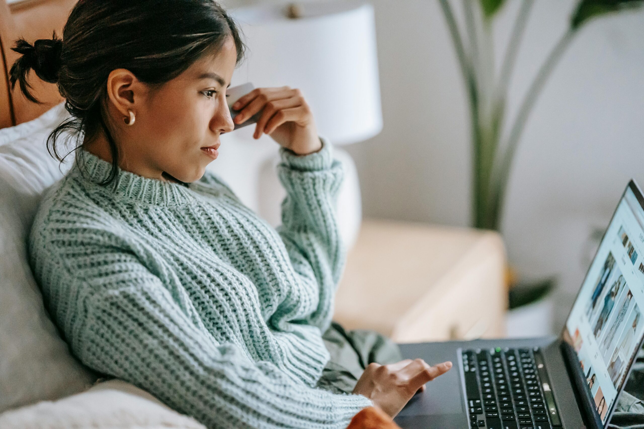 Woman laid on her bed browsing the best apparel websites to buy clothing.